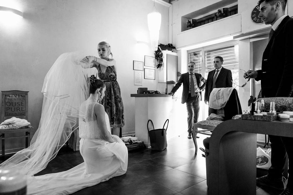 Una damigella sistema il velo della sposa