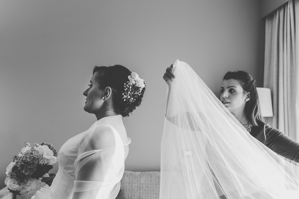 Una damigella indossa il velo da cerimonia alla sposa