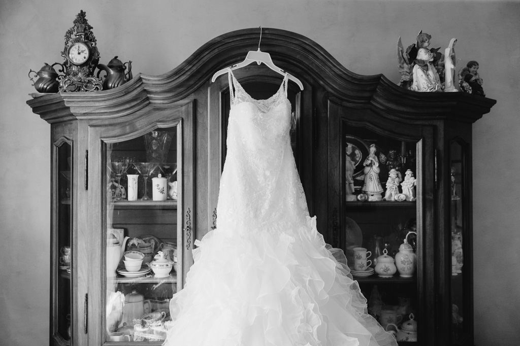 L'abito della sposa Giorgia appeso su un armadio antiquato con all'interno oggetti di porcellana