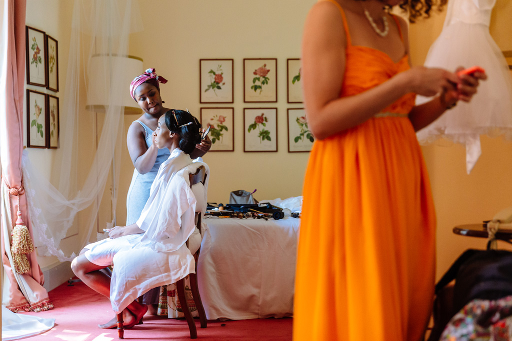 La damigella acconcia la sposa in camera durante la preparazione