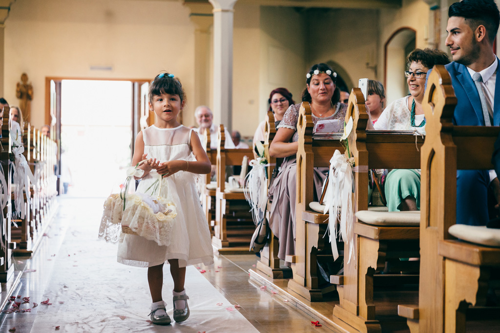 Una bambina attraversa il corridoio con petali di rose supportate da un cestino