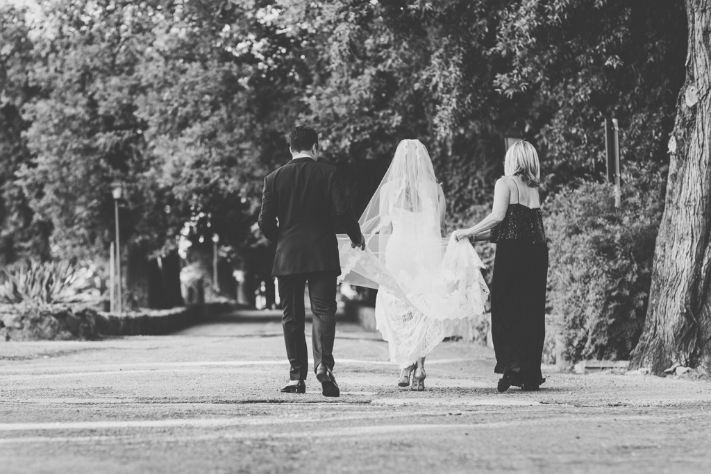 La madre sostiene il vestito da matrimonio della sposa durante una passeggiata