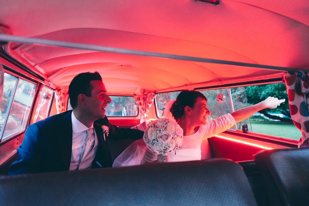 Lo sposo e la sposa sono pronti a scendere dalla macchina illuminati da una luce rossa al neon