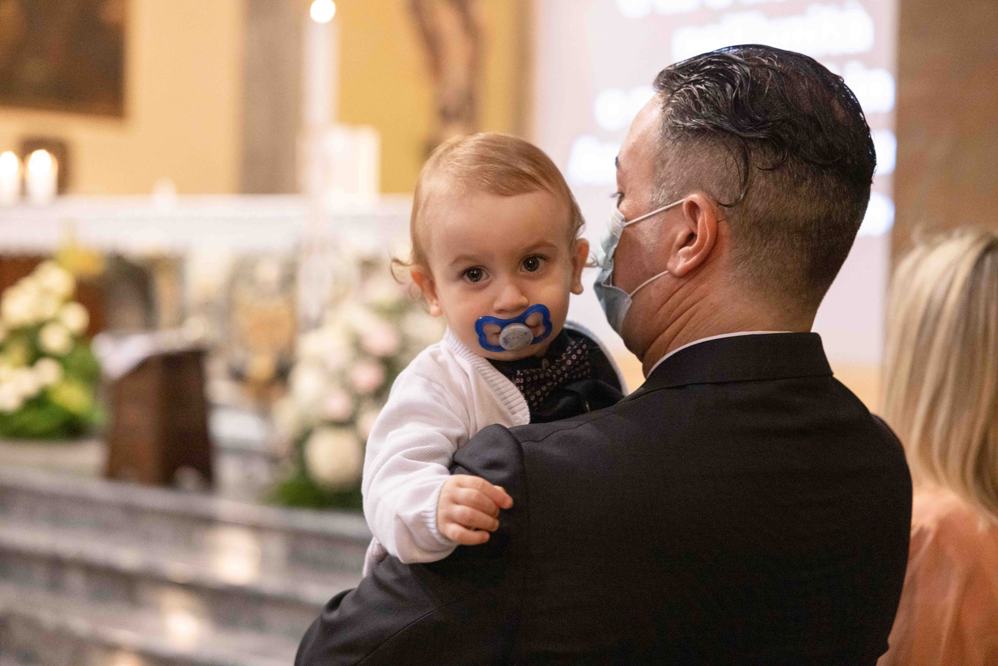 Bambino e padre durante la celebrazione del battesimo nella Invitati al battesimo nella Parrocchia di Comenduno nei pressi di Bergamo