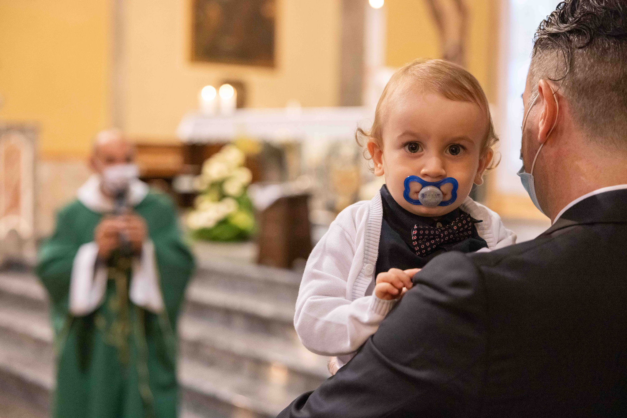 Bambino e padre durante la celebrazione del battesimo nella Invitati al battesimo nella Parrocchia di Comenduno nei pressi di Bergamo
