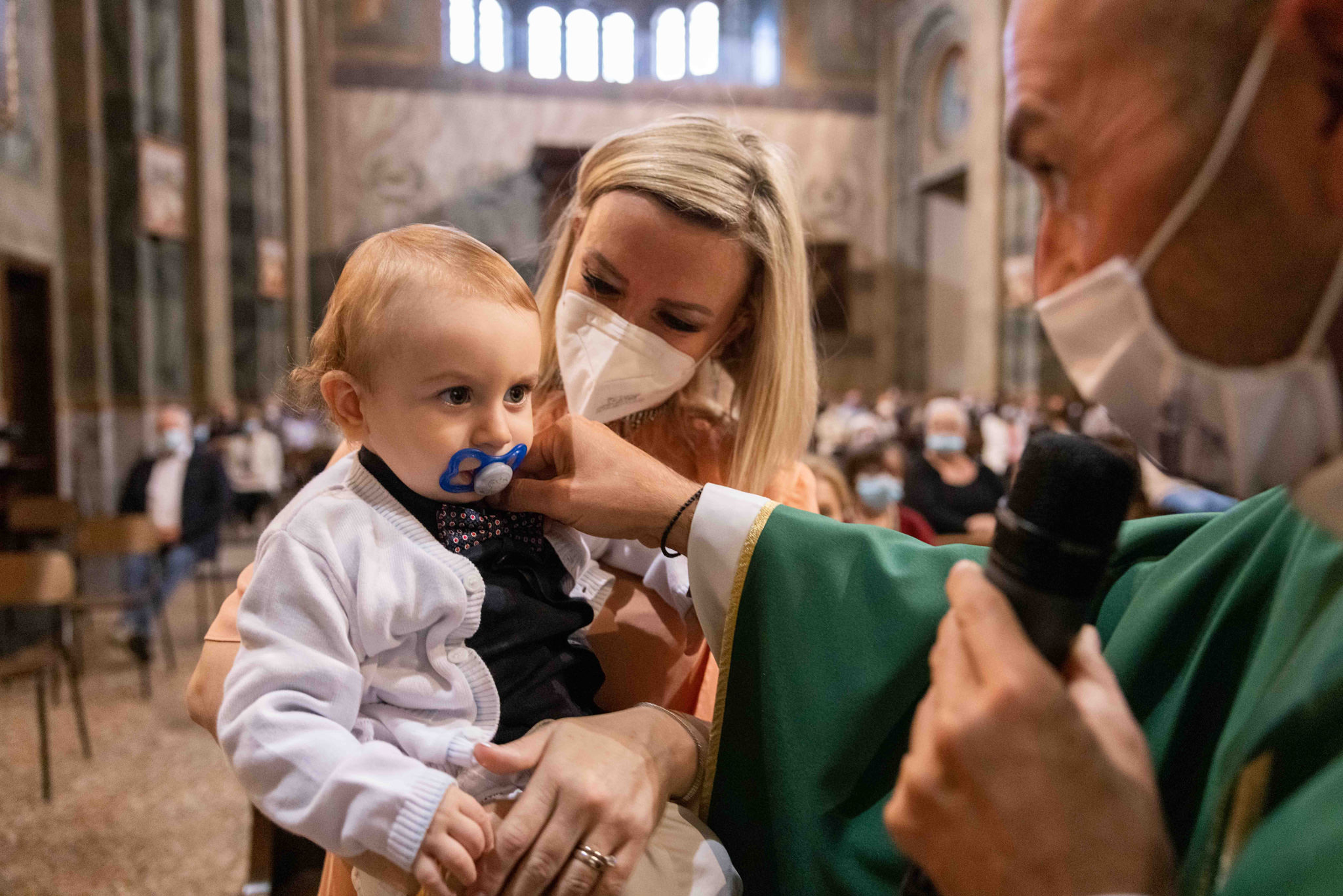 Bambino e sacerdote durante la celebrazione del battesimo