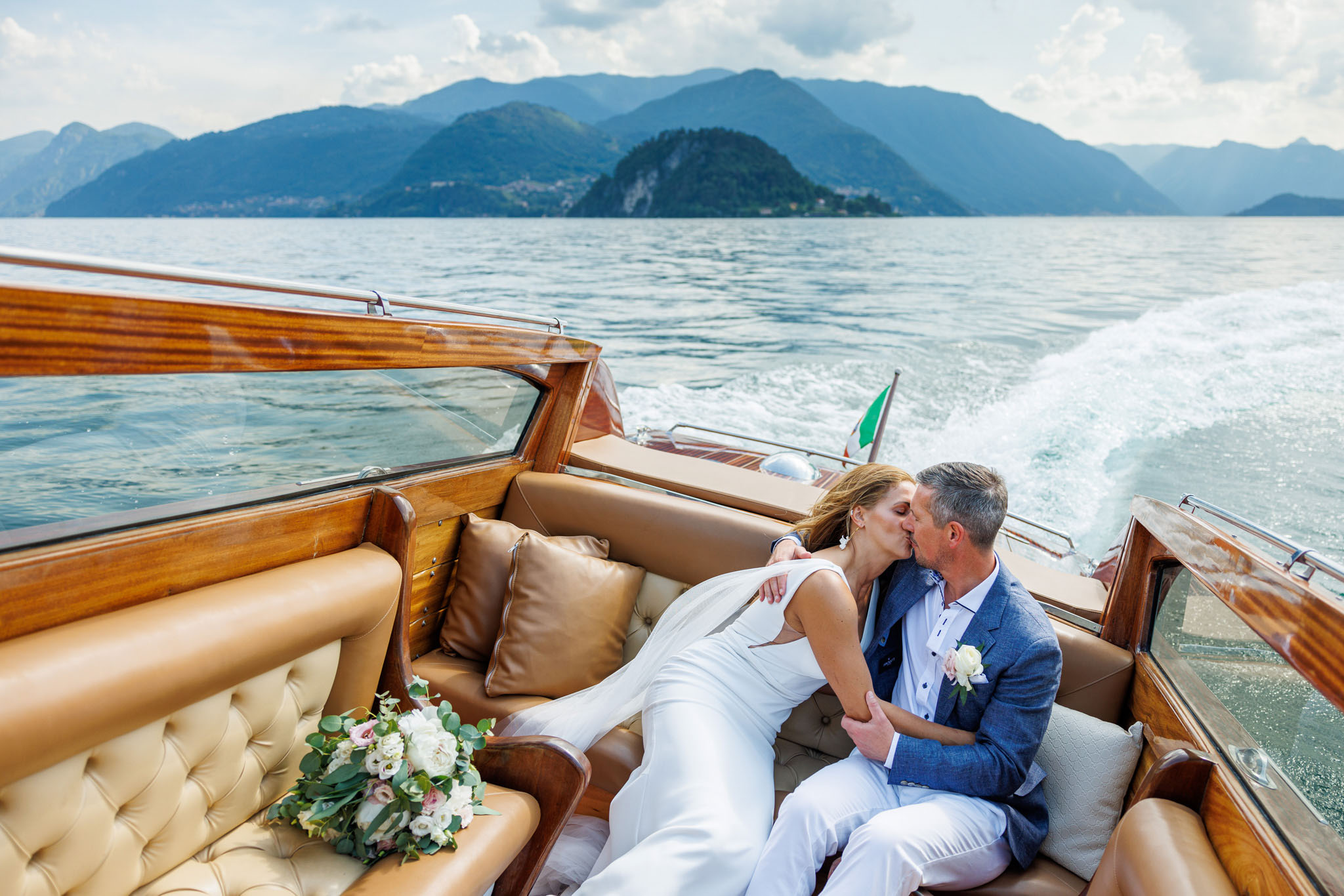 Gli sposi che si baciano in barca sul lago di como al loro matrimonio