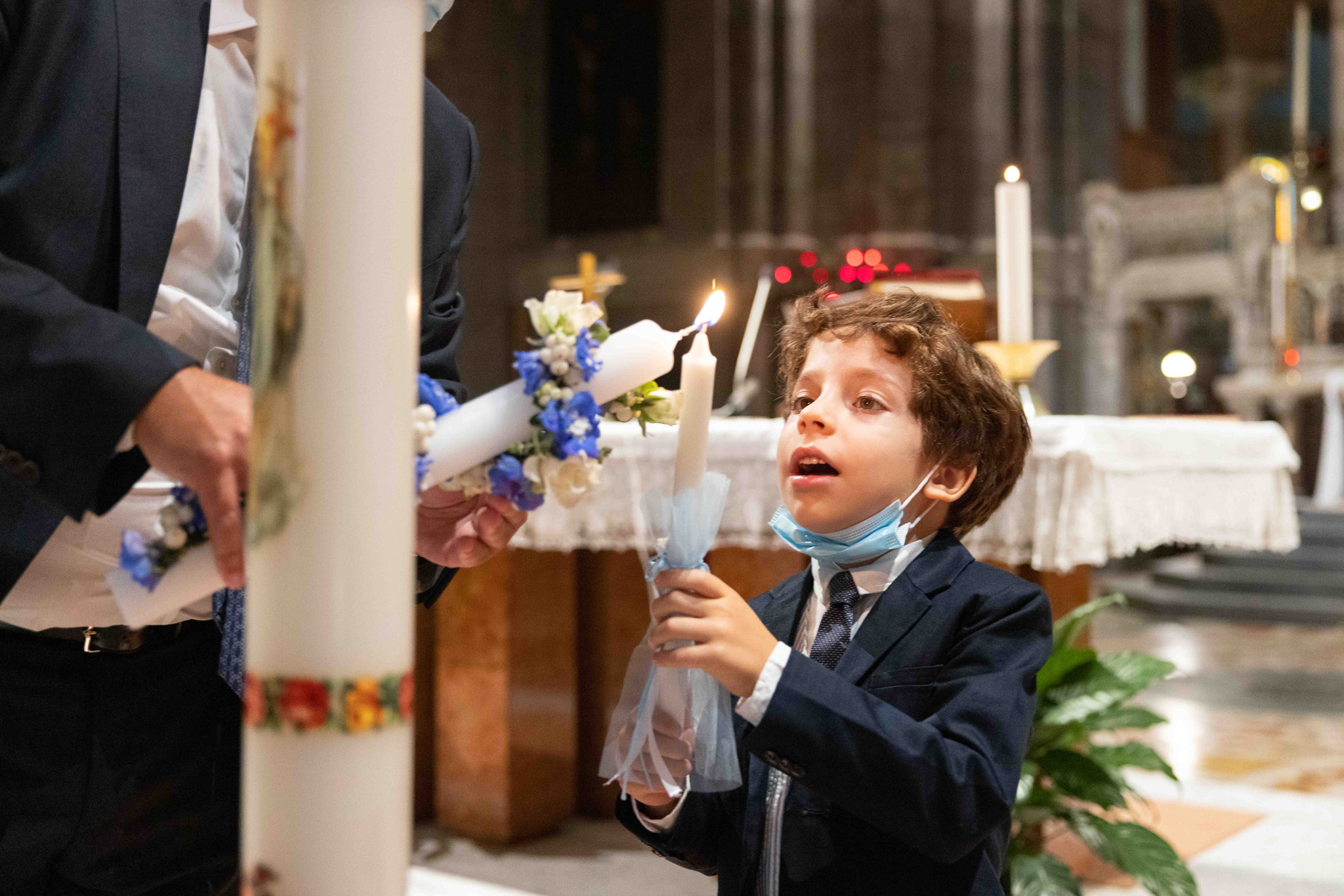Il fratello del bambino che accende la candela in Basilica Parrocchiale Corpus Domini a Milano