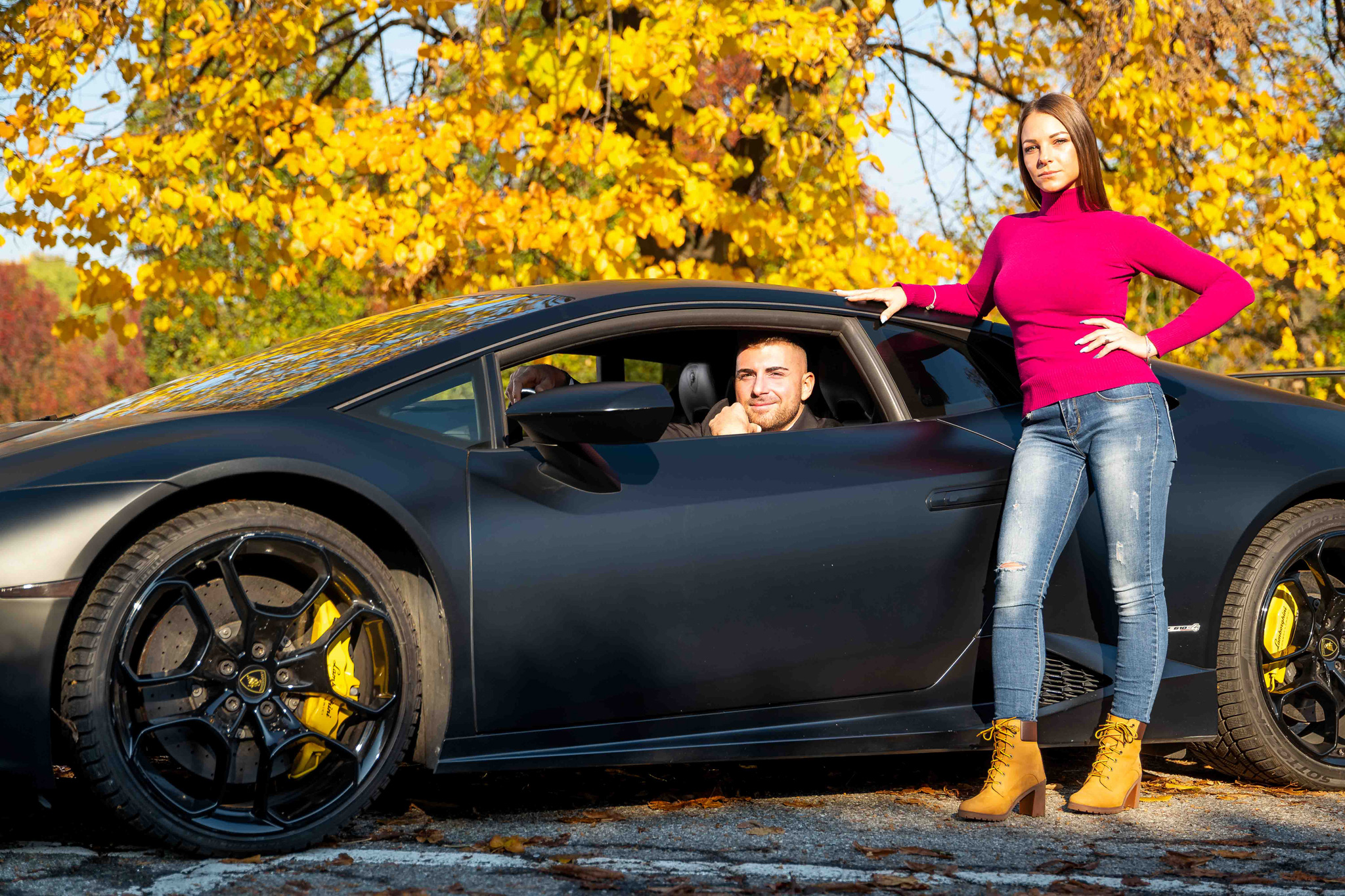Donna e uomo insieme alla loro lamborghini in esterna